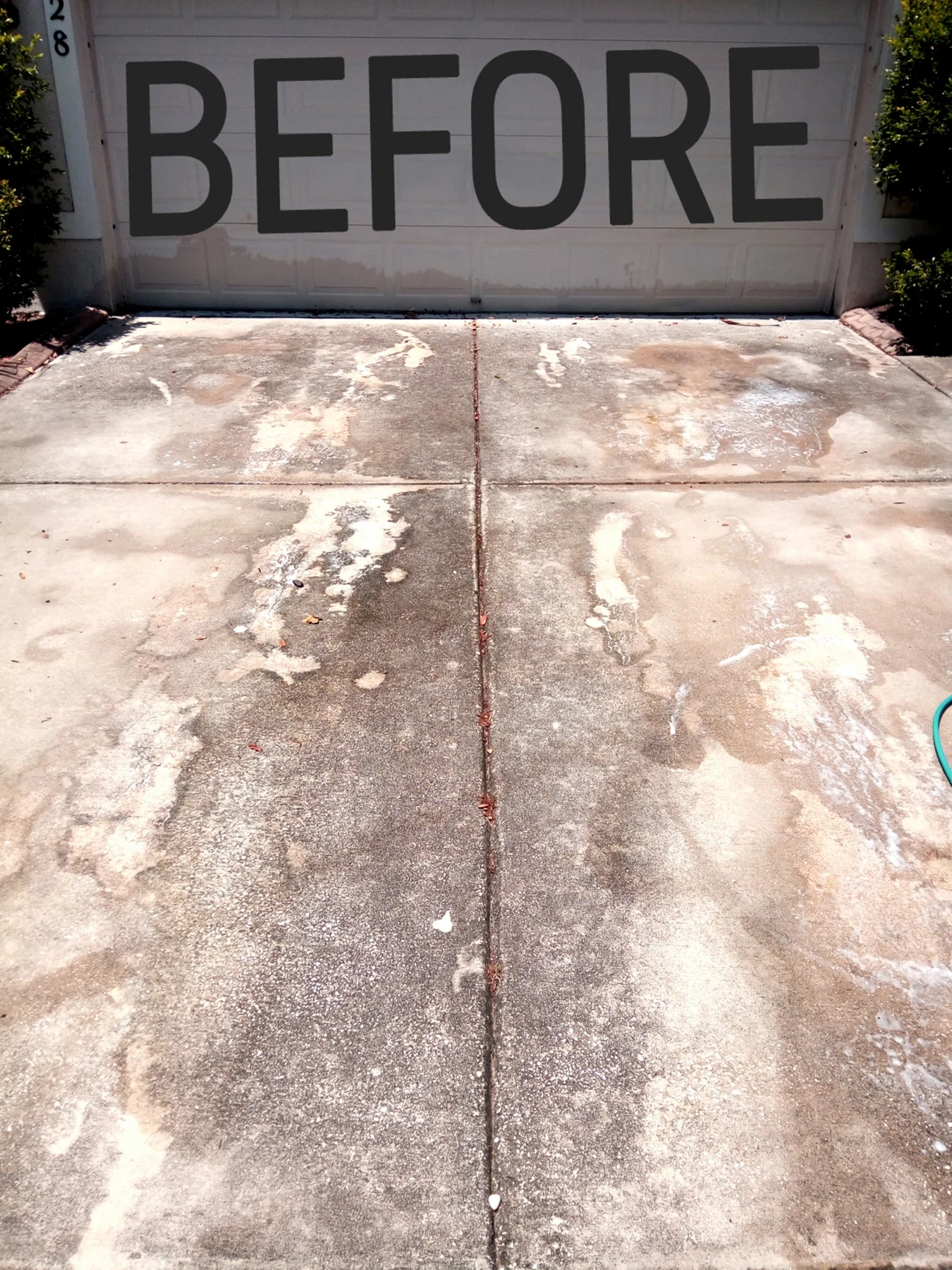 Driveway before pressure washing, showing dark buildup across the concrete